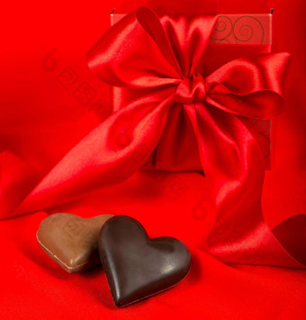 巧克力心礼物盒子丝带红色的丝绸背景黑色的牛奶巧克力