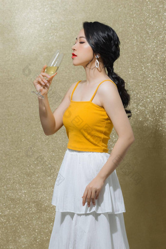 肖像快乐的年轻的亚洲女人喝酒孤立的黄金背景