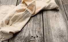 折叠米色亚麻毛巾表格使灰色的木董事会前视图
