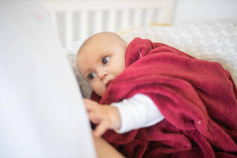位穿着运动服婴儿覆盖红色的毯子说谎床上