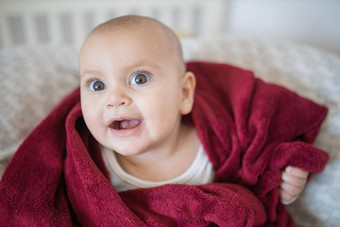 快乐婴儿覆盖红色的毯子说谎床上