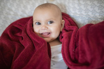 快乐婴儿覆盖红色的毯子说谎床上