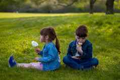 男孩女孩坐着草吃冰奶油