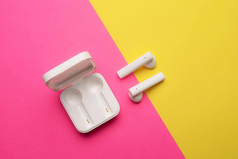 无线耳机粉红色的背景明亮的背景白色耳机蓝牙耳机粉红色的黄色的背景复制空间现代技术
