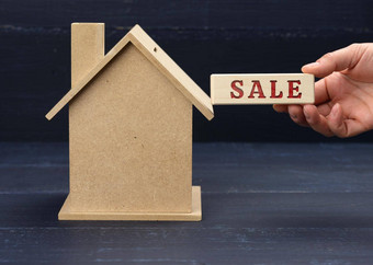 木模型房子手持有块登记出售蓝色的背景房子出售概念真正的房地产投资