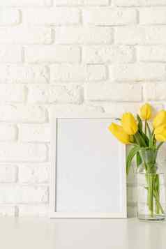 黄色的郁金香玻璃花瓶空白照片框架白色砖墙背景