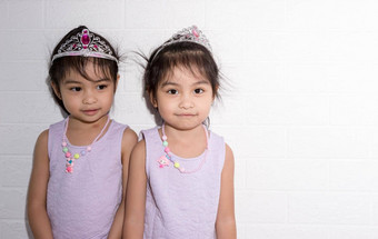 女亚洲相同的双胞胎坐着椅子白色背景穿紫色的衣服配件站一边一边
