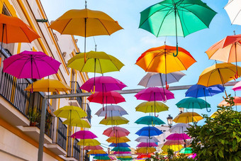 色彩鲜艳的雨伞城市街装饰挂色彩斑斓的雨伞蓝色的天空旅游吸引力