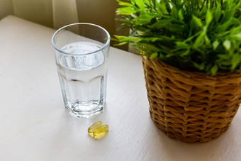 ω螺旋藻叶绿素胶囊玻璃水白色木表格饮食补充生物活跃的添加剂维生素药片健康支持
