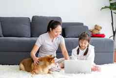 芝犬儒狗感兴趣女孩有趣的移动PC坐妈妈。生活房间保持首页防止感染疾病流感大流行