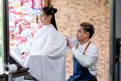 亚洲美沙龙理发师男人。坐过程头发减少长头发客户集中注意力工作概念美业务好人