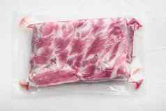 新鲜的猪肉肋骨塑料包白色石头背景前视图平躺