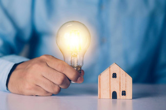 商人持有光灯泡首页木解决方案创新环境思考的想法规划买房子住宅生态储蓄能源业务金融概念