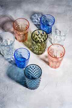 色彩斑斓的在上雕琢平面的几何喝玻璃集团空绿色红色的蓝色的透明的饮料器皿饮料石头混凝土背景角视图