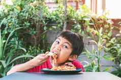 亚洲可爱的男孩幸福的坐着吃披萨