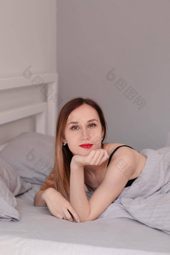 漂亮的红色头发的人女人黑色的花边内衣床上灰色表