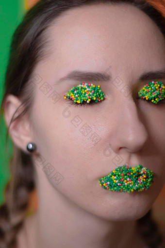 年轻的女人肖像糖果化妆五彩缤纷的糕点一流的珍珠嘴唇眼皮绿色橙色背景复活节主题