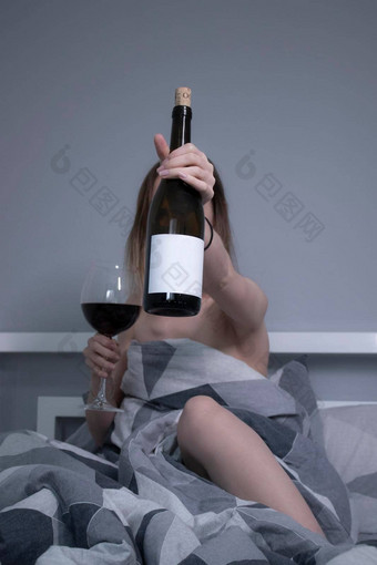 快乐美丽的纤细的半裸的女孩显示瓶酒<strong>标签</strong>床上灰色的表<strong>三角</strong>形