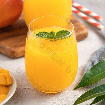 新鲜的美丽的美味的芒果汁奶昔玻璃杯灰色的表格背景