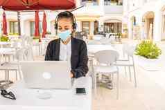 企业家女人工作户外酒吧表格移动PC穿保护医疗脸面具由于社会距离科维德流感大流行正常的工作移动无线网络技术
