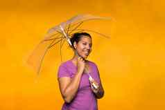 年轻的有吸引力的混合比赛女人持有伞穿紫色的衬衫黄色的背景