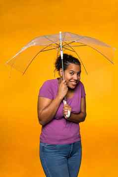 年轻的有吸引力的混合比赛女人持有伞穿紫色的衬衫黄色的背景