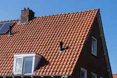 屋顶红色的屋顶瓷砖烟囱太阳能面板使可再生能源清晰的蓝色的天空