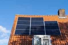 屋顶红色的屋顶瓷砖太阳能面板使可再生能源清晰的蓝色的天空