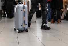 旅行者年轻的男人。腿走携带手提箱机场乘客等待距离