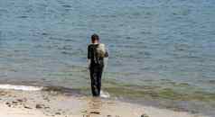 渔夫走海滩携带网肩膀