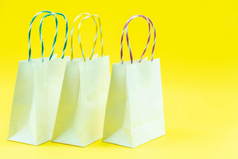 色彩鲜艳的纸购物袋孤立的黄色的背景特写镜头拍摄白色购物袋