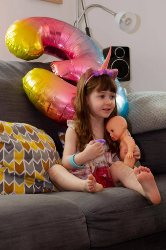 可爱的婴儿女孩坐着沙发色彩鲜艳的气球娃娃