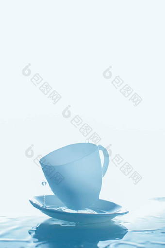 蓝色的杯飞碟溅水垂直照片玻璃水蓝色的背景