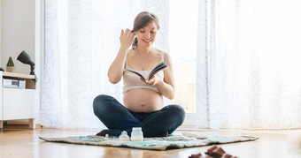 阅读怀孕快乐怀孕了妈妈。坐着地板上阅读书