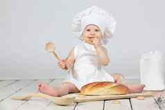 孩子烹饪美丽的女孩烹饪衣服长面包木勺子面粉孩子一年有趣的婴儿老板概念烘焙面包店产品
