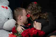美丽的年轻的夫妇首页拥抱吻享受支出时间庆祝情人节一天红色的玫瑰泰迪熊