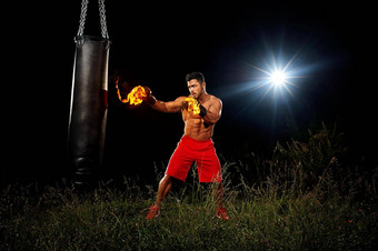运动员培训黑色的晚上背景肌肉发达的身体拳击手套火晚上培训培训开放空间草拳击踢手黑色的冲袋