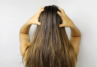 年轻的女人应用头发石油手指<strong>加油</strong>头发洗头发护理概念