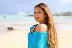 微笑年轻的女人覆盖蓝色的毛巾放松海滩夏天假期概念