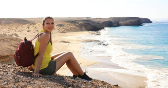 旅行兰斯洛特年轻的背包客女人坐着岩石playas游船上海滩大西洋海洋背景全景横幅视图