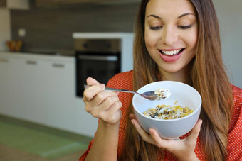 关闭美丽的年轻的女人吃斯凯尔yougurt麦片牛奶什锦早餐水果首页焦点模型眼睛室内图片健康的食物概念