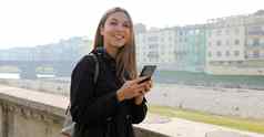 年轻的女人聊天应用程序移动电话参观欧洲小镇旅行相机女旅游导航地图智能手机城市河