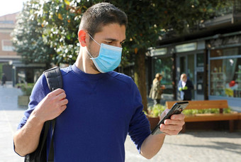 科维德流感大流行冠状病毒年轻的男人。穿外科手术面具聪明的电话应用程序城市街援助联系跟踪诊断响应冠状病毒流感大流行