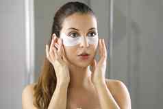 美女人应用黑眼圈面具镜子浴室皮肤护理女孩触摸补丁织物面具眼睛减少眼睛袋