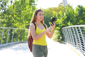 年轻的背包客女孩检查全球定位系统(gps)<strong>坐标</strong>移动电话自然公园生态旅游概念
