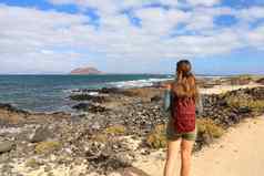 后视图年轻的女背包客徒步旅行海Fuerteventura岛西班牙