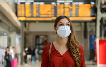 旅行者女人穿断续器脸面具火车站保护病毒烟雾年轻的高加索人女人时间表信息离职移民