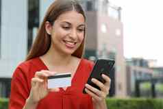 年轻的女人持有信贷卡聪明的电话在线购物电子商务互联网银行支出钱工作聪明的电话应用程序