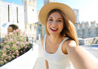 微笑年轻的旅游女人需要肖像Sirmione意大利美丽的时尚女孩需要自拍照片Sirmione城堡背景湖加尔达意大利