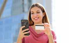关闭很高兴不错的女人持有信贷卡智能手机在户外
